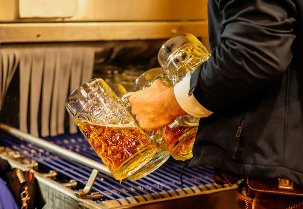 A waiter with a handful of giant beer mugs or Mas at Oktoberfest in Munich, Germany