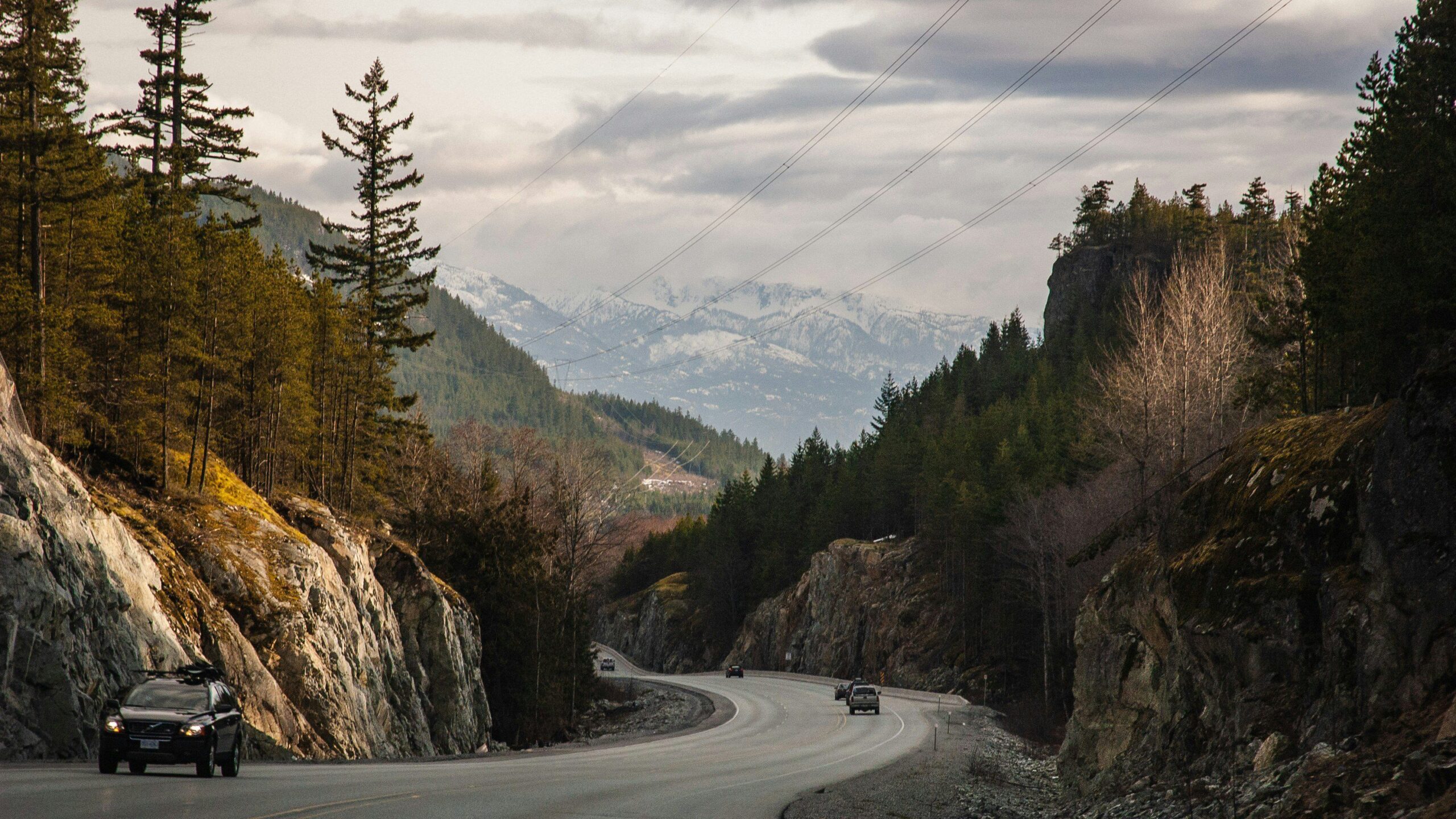 Cars driving through the Sea to Sky Highway on route to the snow capped Rocky Mountains.