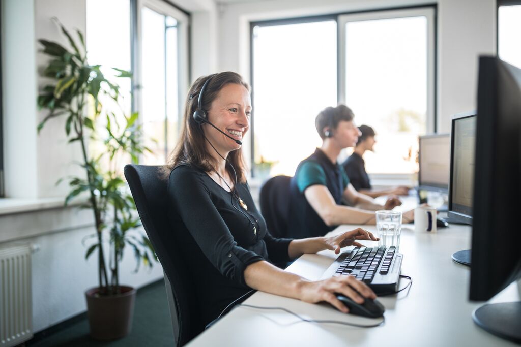 Customer service person with a headset on sitting at a computer in an office