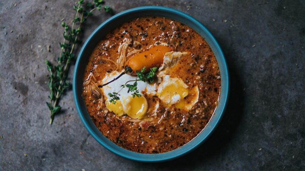 Creamy Peruvian Ají de Gallina chicken stew with egg and olive garnish.