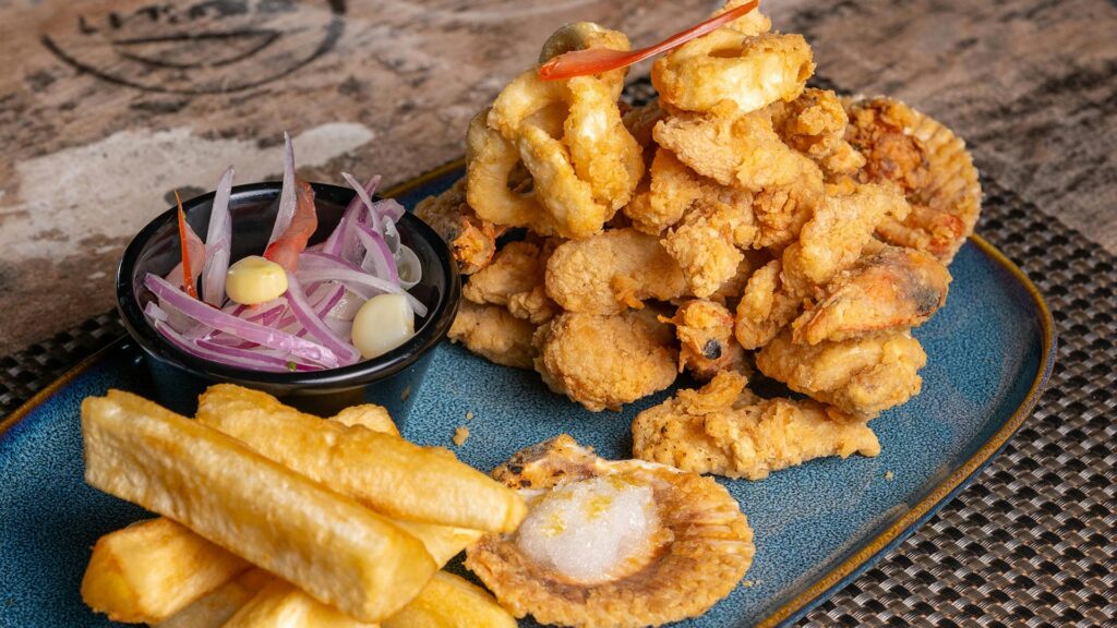 Large platter of deep-fried mixed Peruvian seafood (Jalea Mixta) with onion relish.