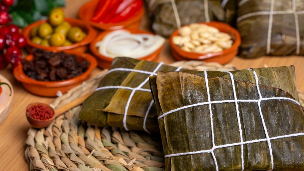 Steamed Tamales Peruanos wrapped in banana leaves on a plate.