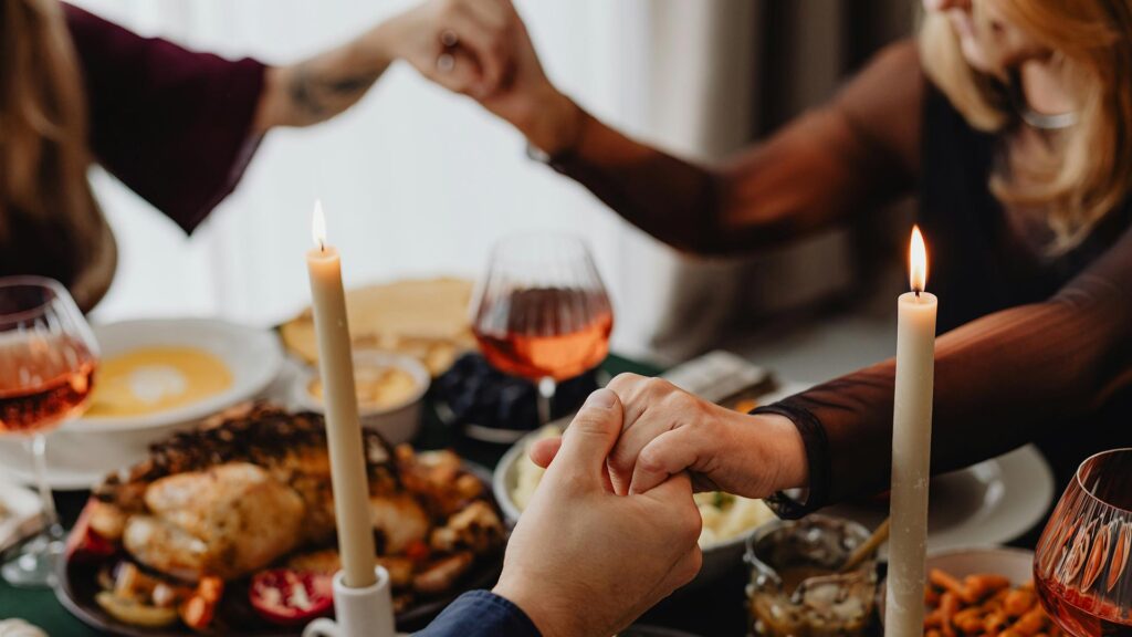 Thanksgiving traditions center around the dining table where people hold hands and give thanks for the meal