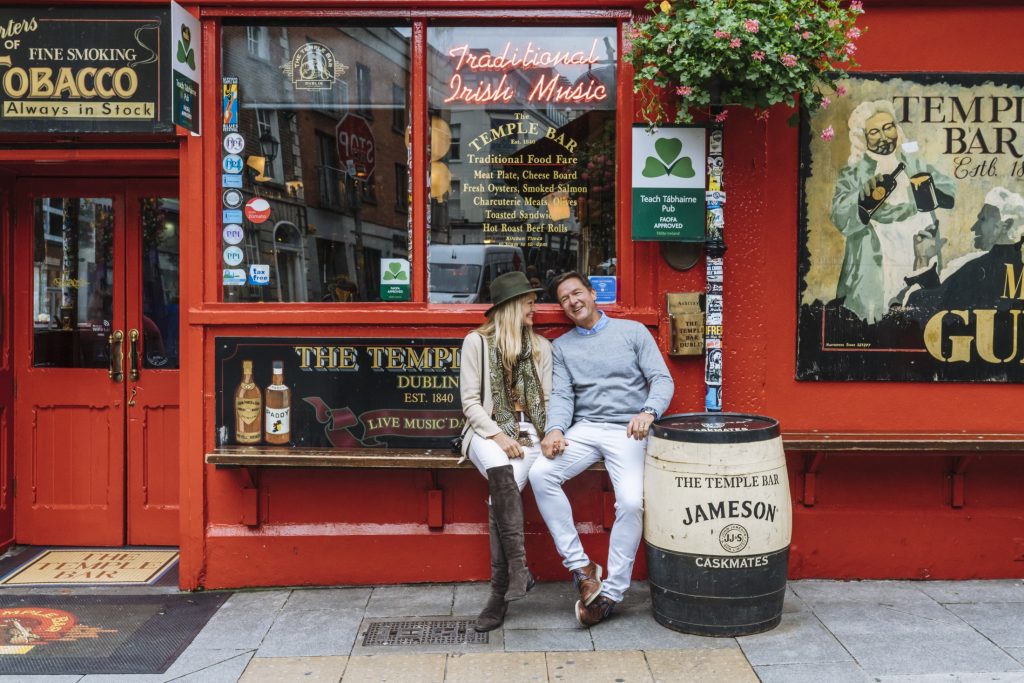 A couple sitting on a bench in front of a red bar in Dublin, Ireland.
