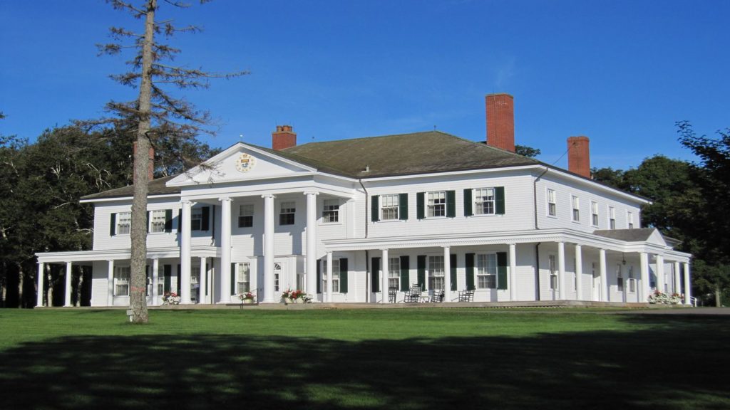 A large white house stands in the middle of a lush green field in Charlottetown, Prince Edward Island.