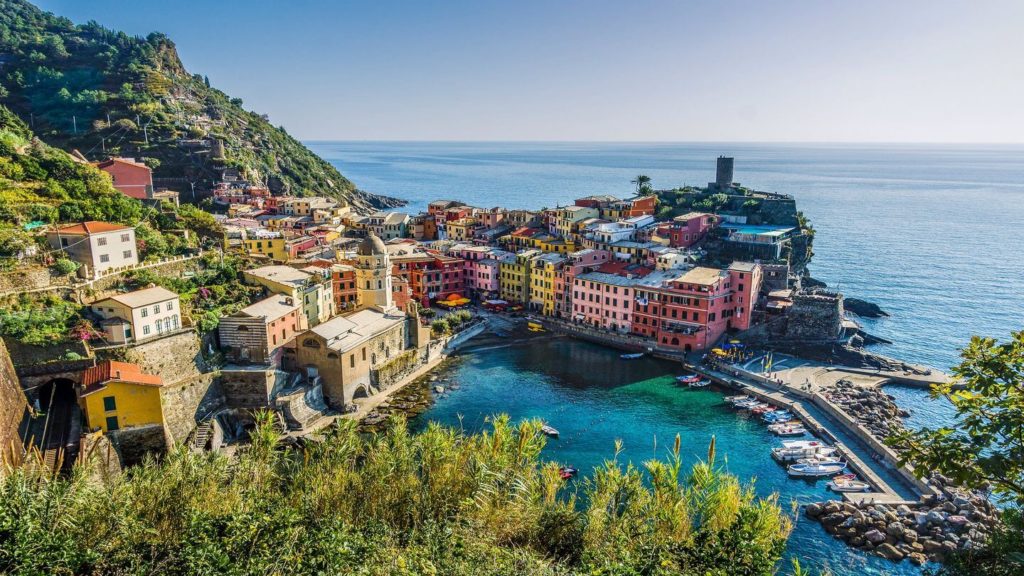 Colorful buildings nestled on a rugged coastline with a small harbor