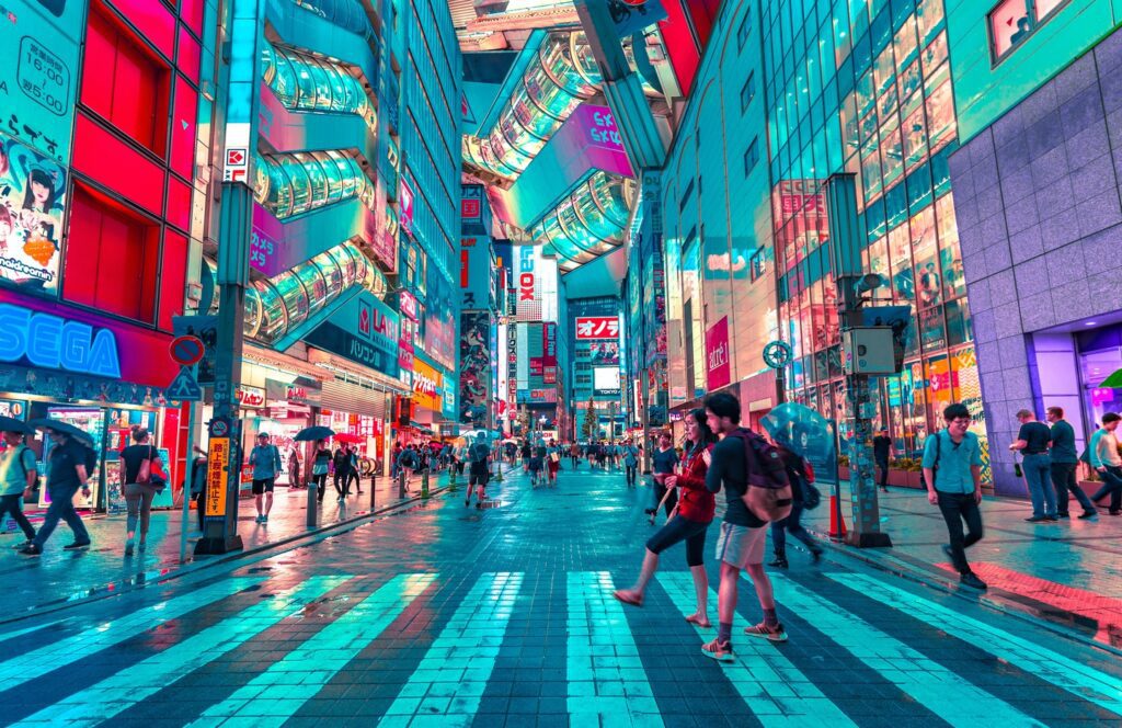 People crossing a road in brightly-lit city street in Japan