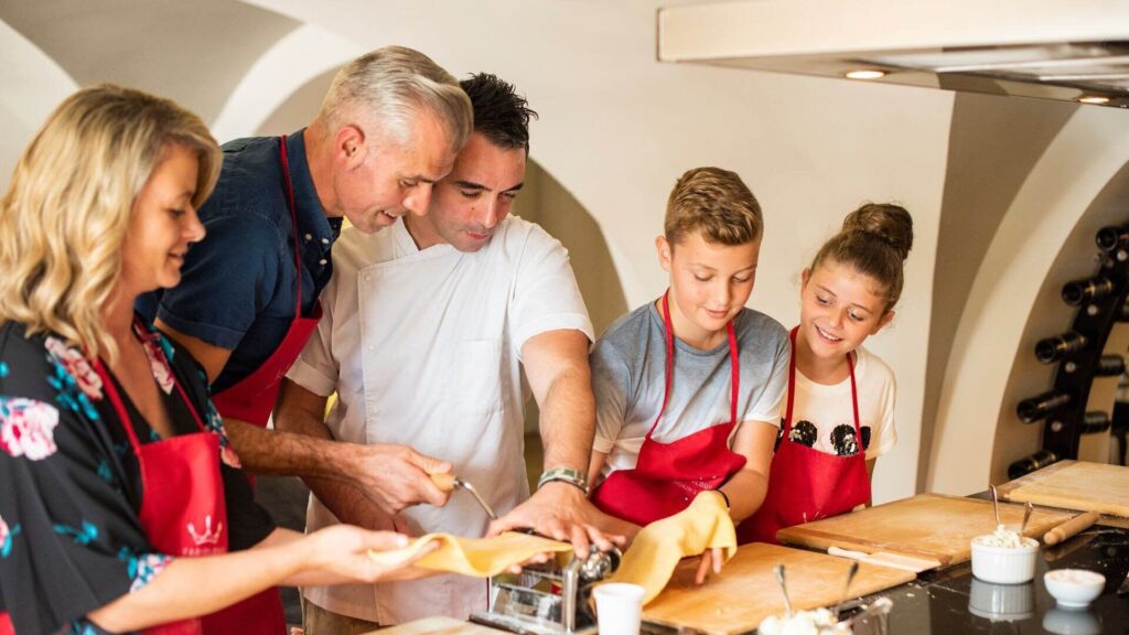 Chef teaching a family to prepare fresh pasta using a mechanical pasta maker