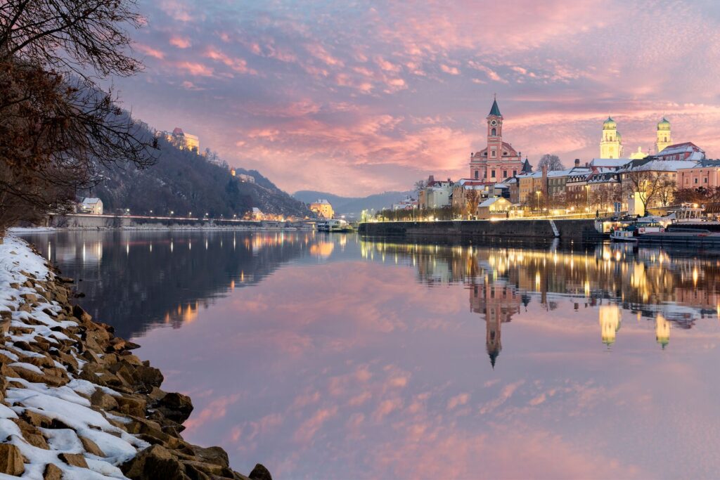 View of buildings across a river with a pink sky above 