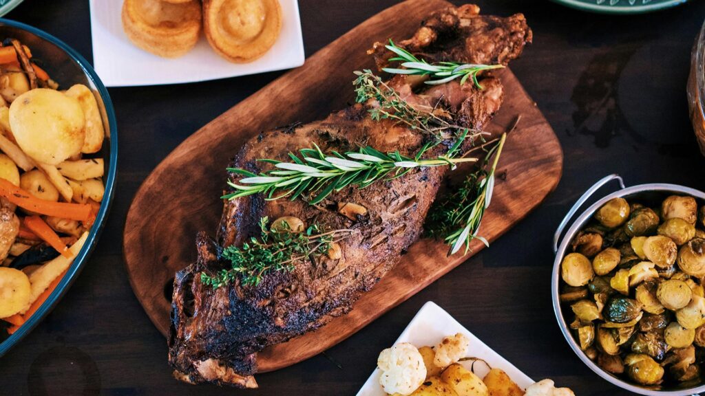 top-down view of leg of roast lamb with fresh herbs