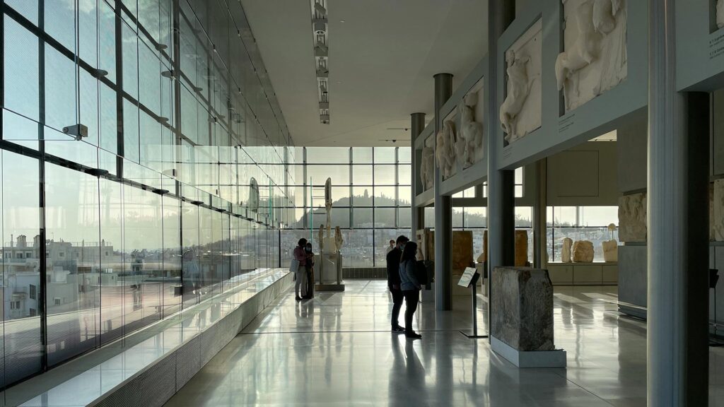 A glass hall at the Acropolis Museum with artifacts inside and views to the Acropolis