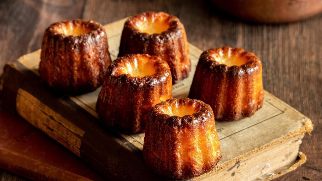 Five golden Canelés sitting on an antique book