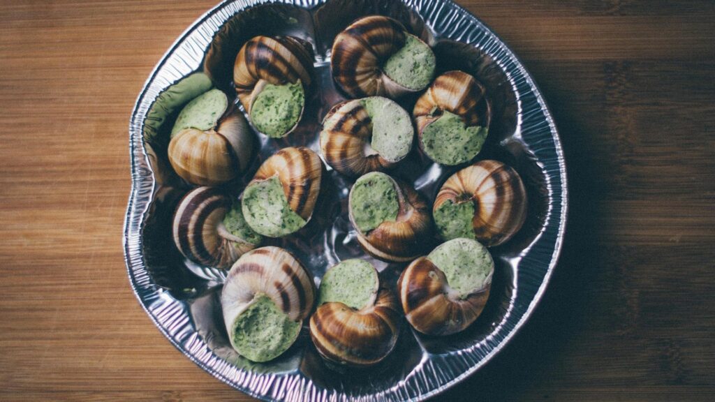 A metal tray of escargot stuffed with a garlicky butter waiting to be grilled