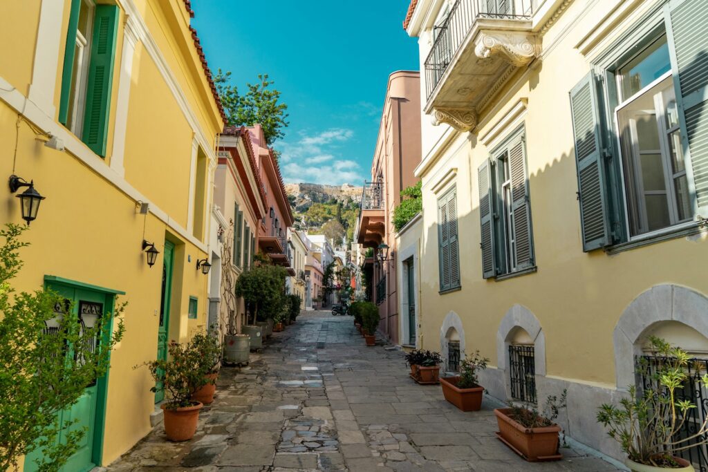 Alleyway lined colourful houses leading uphill to a mountainous backdrop. 