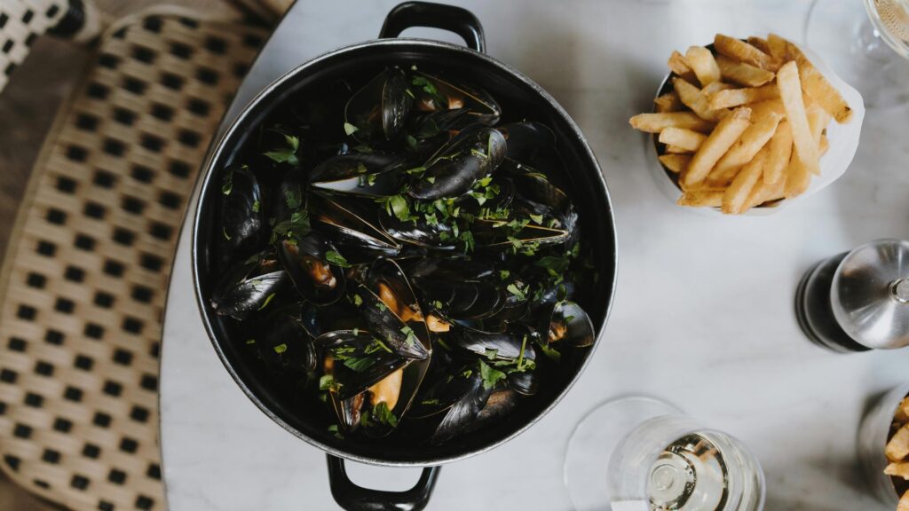 A black pot of Moules or mussels with Frites or french fries on the side
