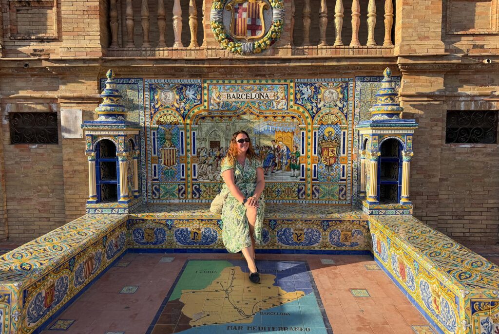 Travel Director Maddy at Plaza de Espana in Seville sitting on the tiled bench that says Barcelona