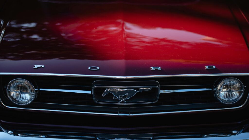 Close up of a red vintage Ford car's bonnet with the horse logo