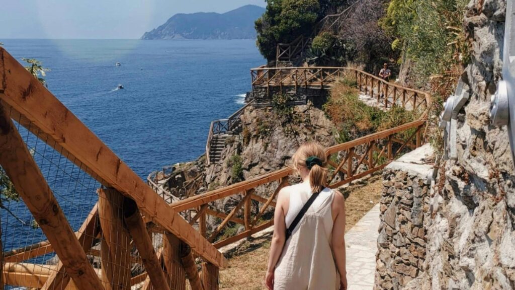 A woman in white walking along the Via dell'Amore walking trail in Cinque Terre Italy