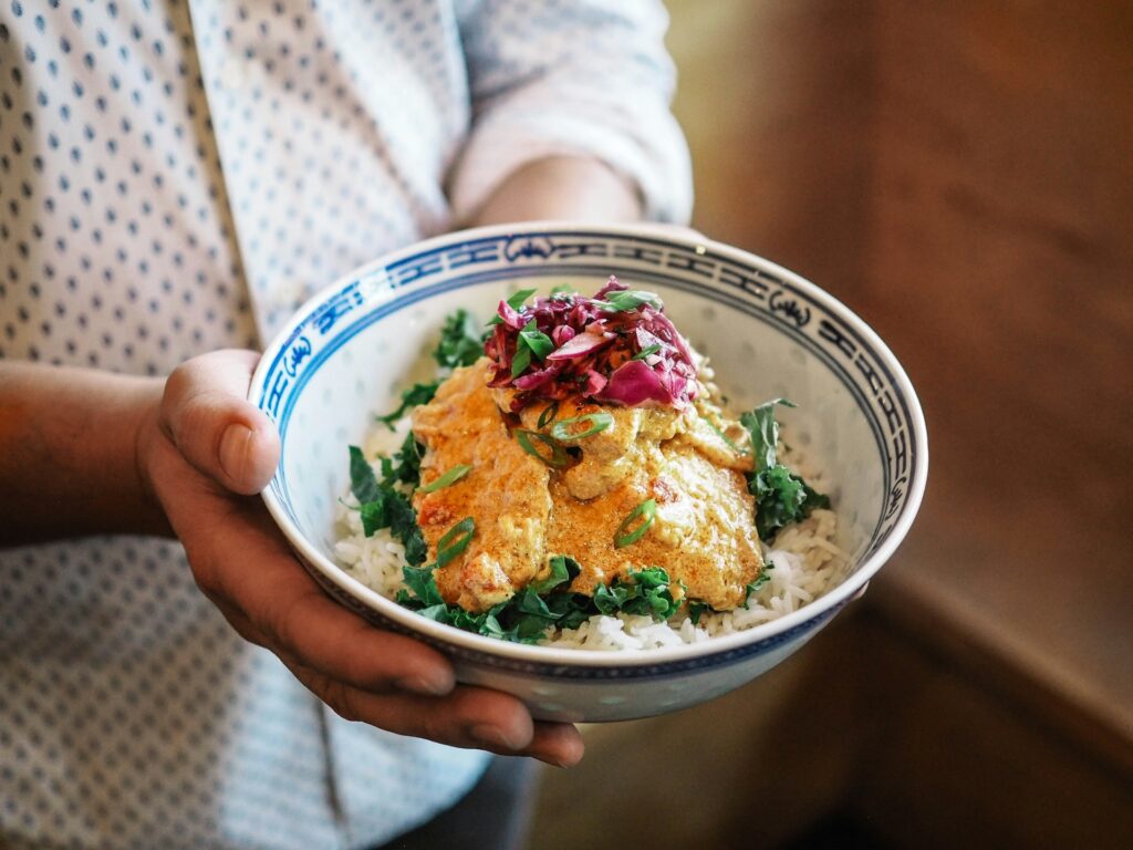 Person holding a bowl of chicken curry