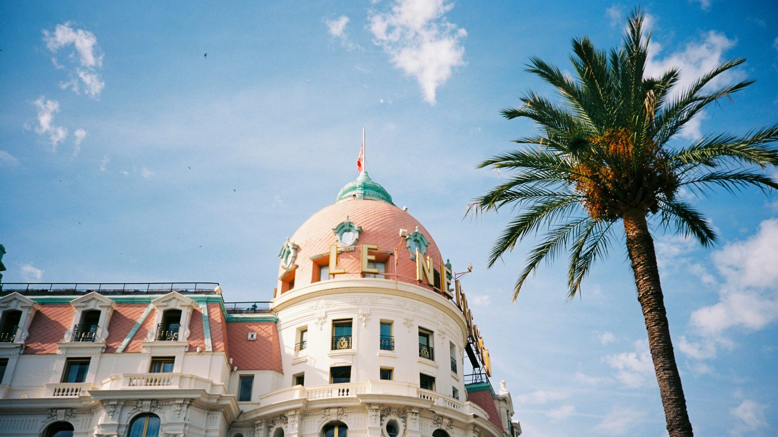 Detail of the facade of an old hotel beside a palm tree