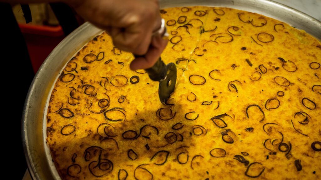 Farinata being cooked and sliced