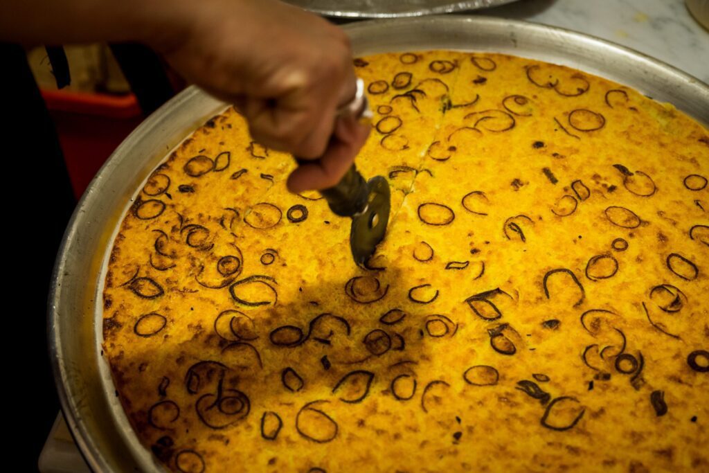 Farinata being cooked and sliced