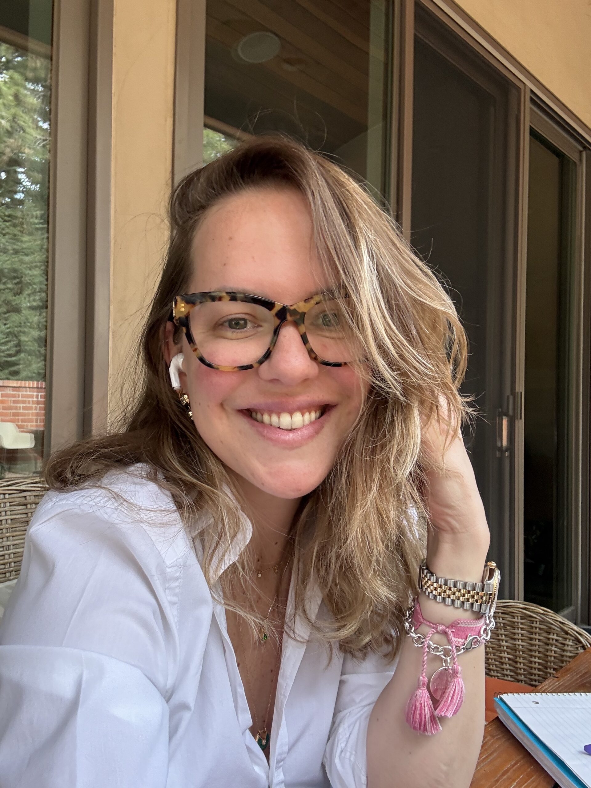 Author portrait of Jen Kaarlo, wearing glasses sitting at an outdoor table