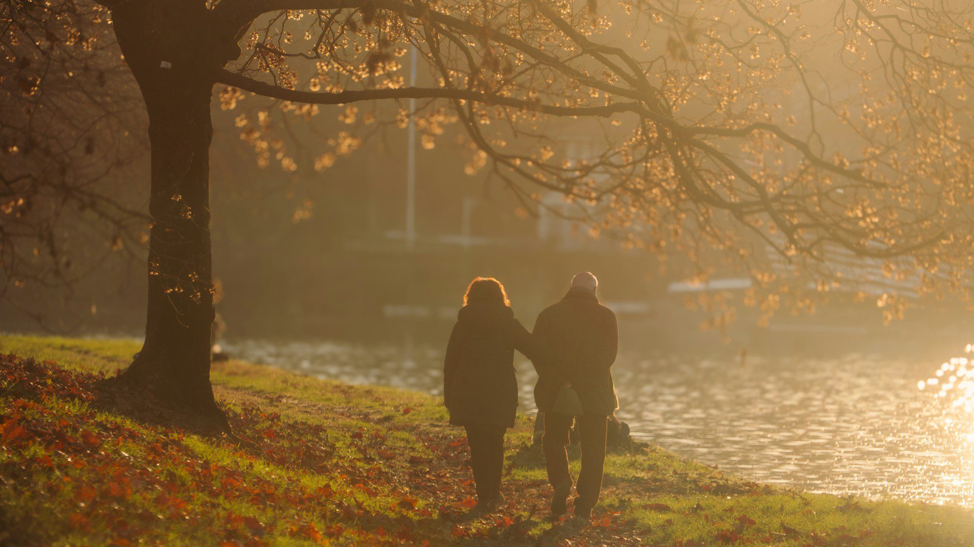 An older couple walking together along the banks of a river