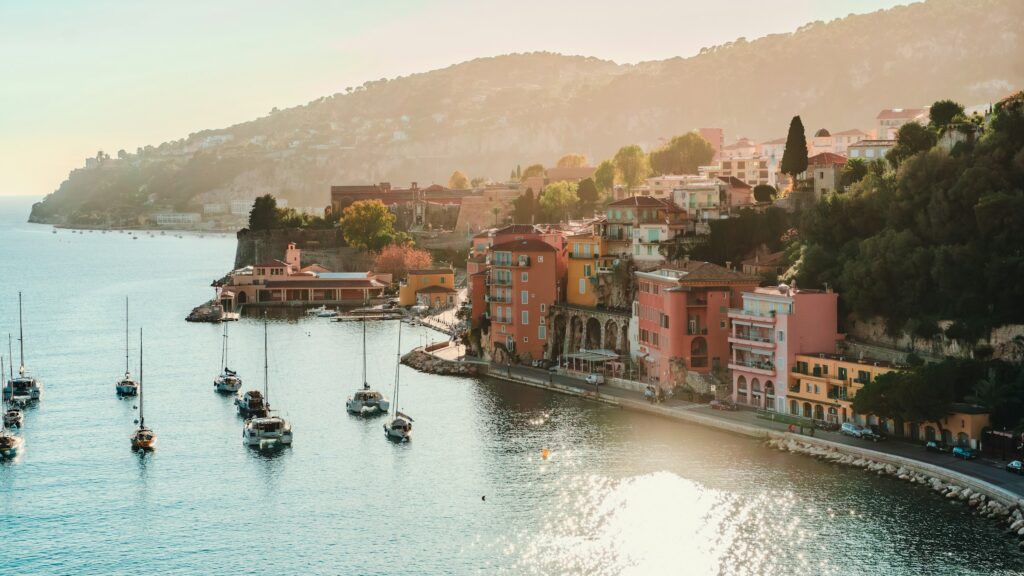 Aerial view of Villefrance-Sur-Mer, with pink houses, sunlight reflected on the water and sail boats