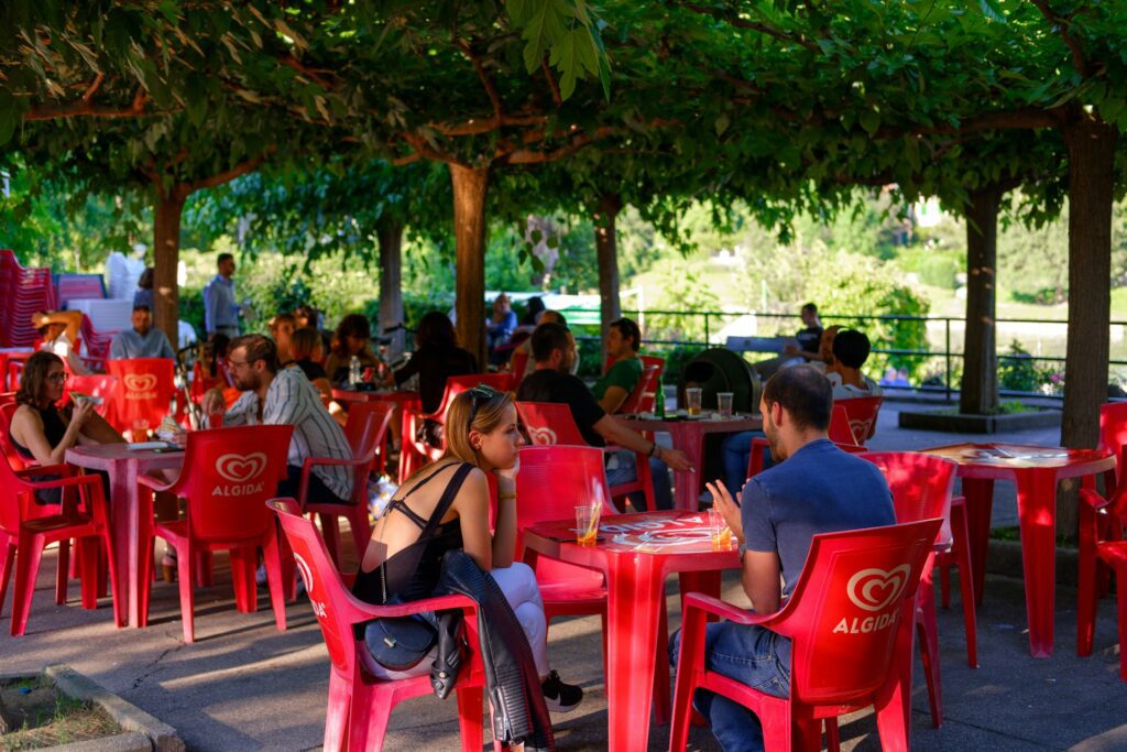 people having drinks at an outdoor cafe under trees