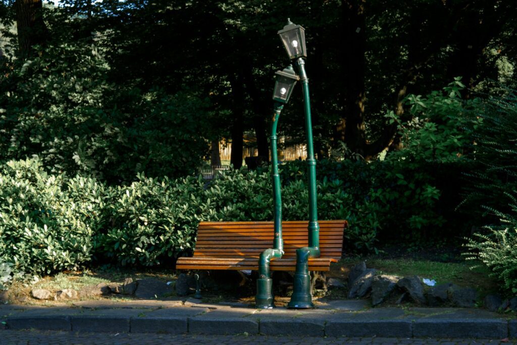 Sculpture of two lamp posts sitting on a park bench