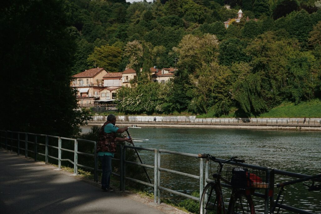 Man fishing on from a pavement overlooking a river