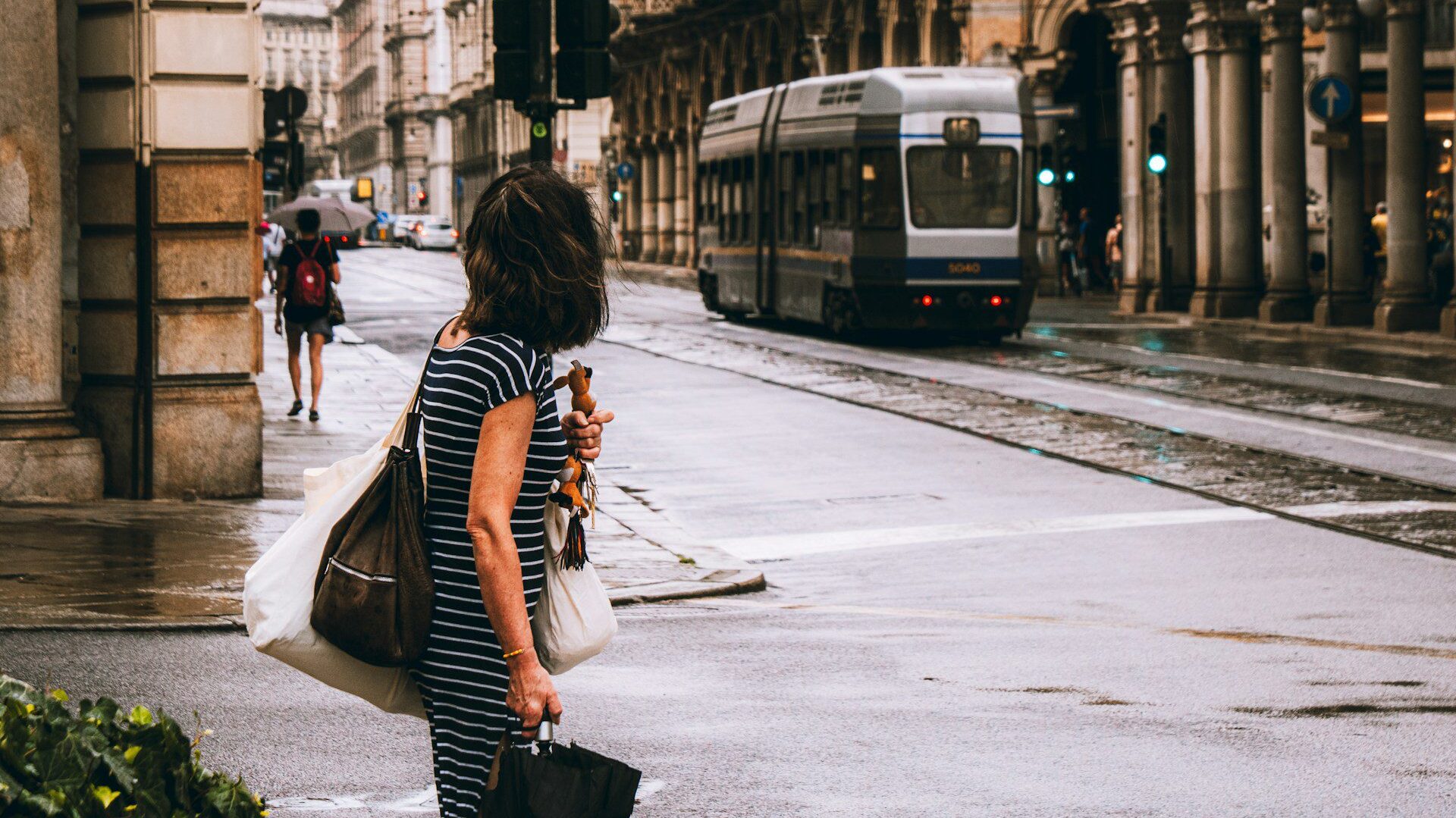 Woman walking in the street with a tram in the background