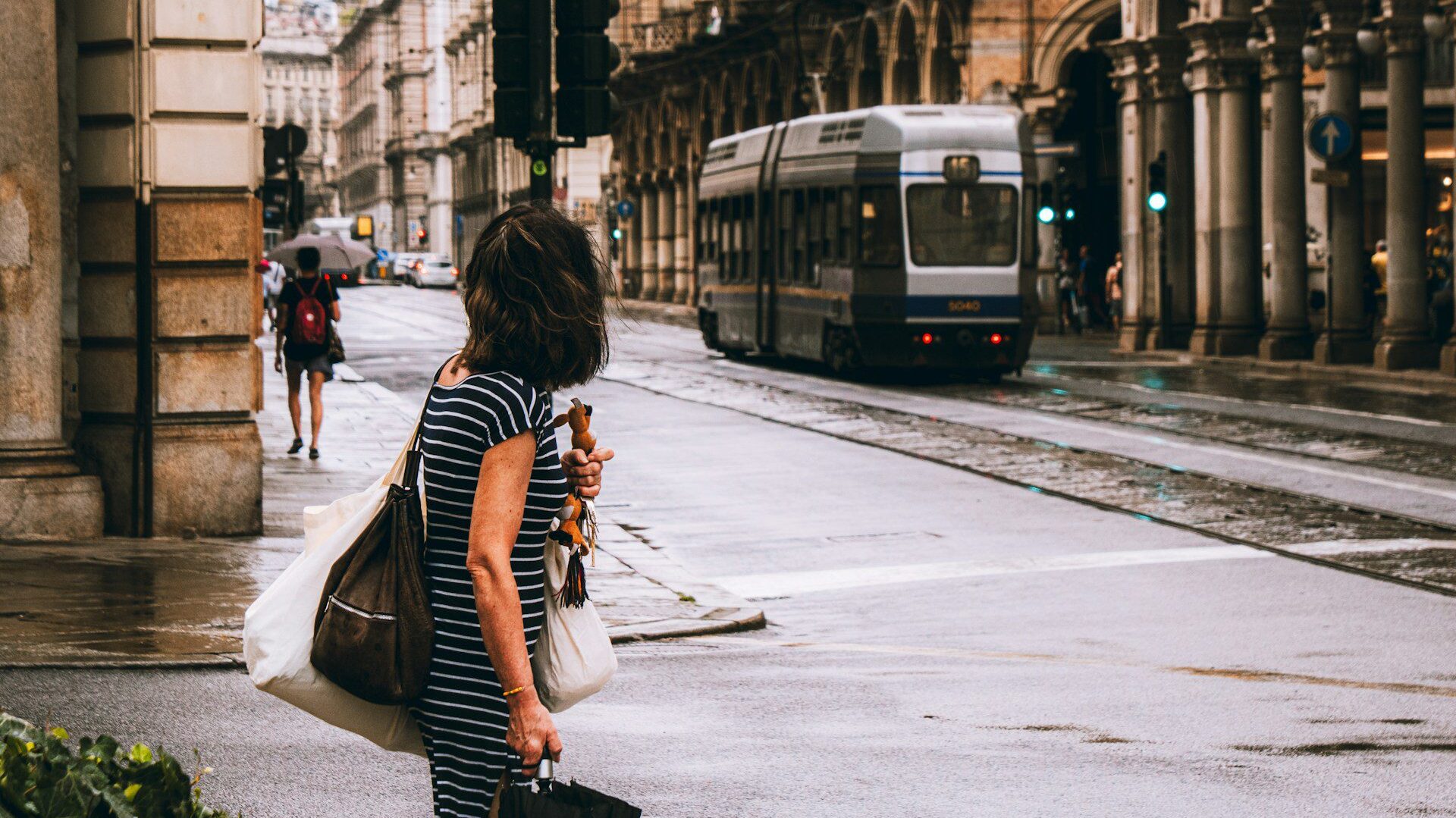 Woman looking down a road towards a tram