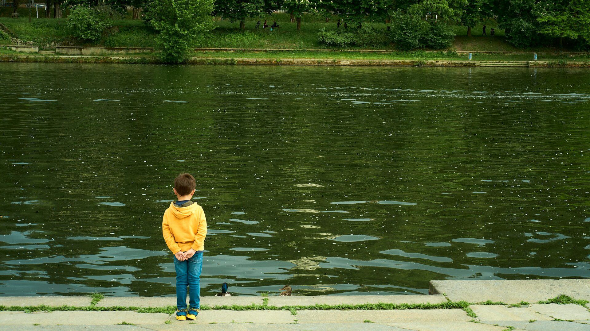 Small boy standing at the edge of a river 