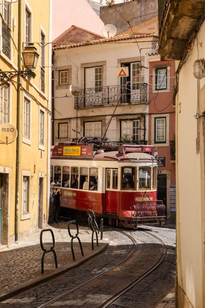 A red vintage tram turning on a tight street in Lisbon