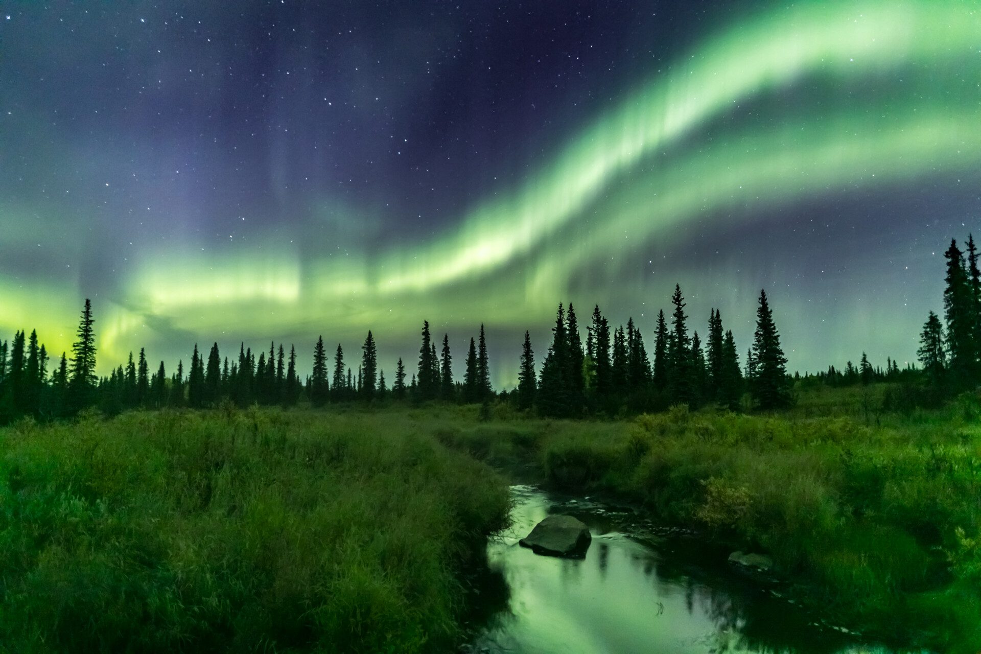 Northern lights over a river through a field