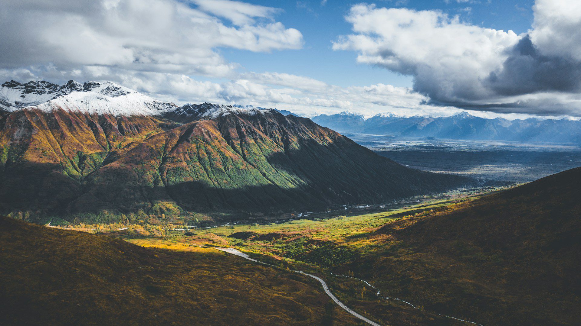 Aerial view of a snow dusted mountain range and valley, with a road threading through