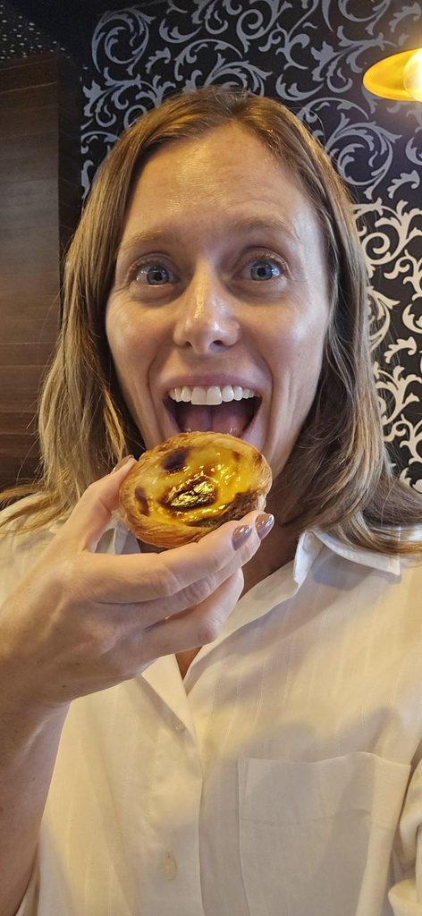 Travel Director Sara eating a custard tart in Portugal.