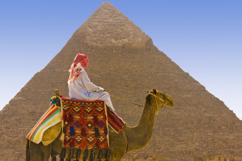 Man on camel in front of Pyramids of Giza, Egypt