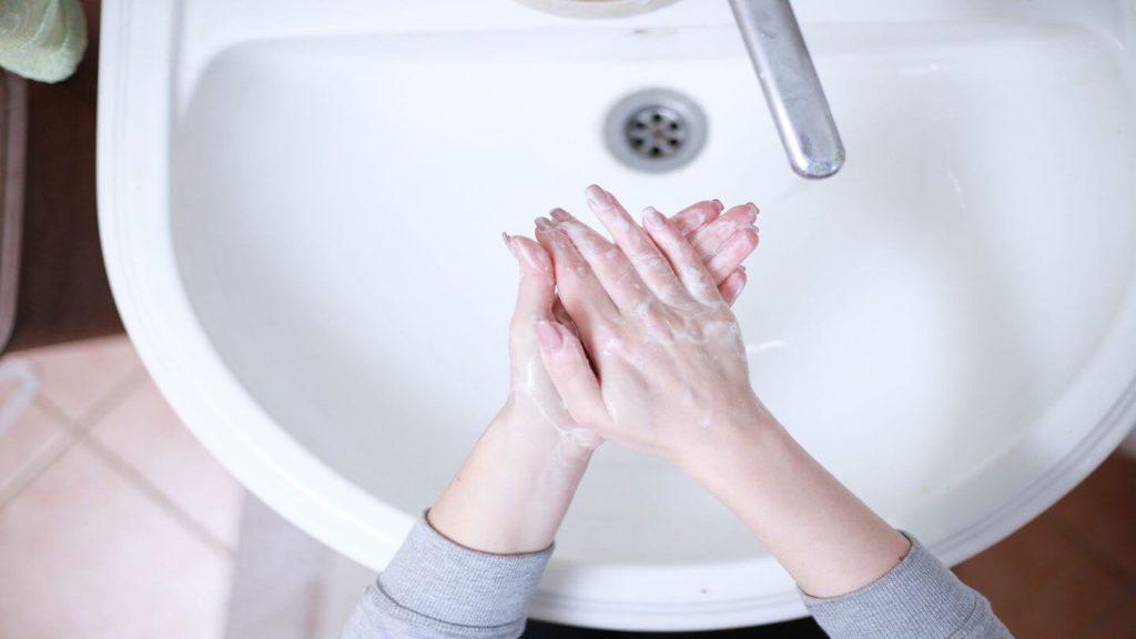 washing hands over sink with water and soap