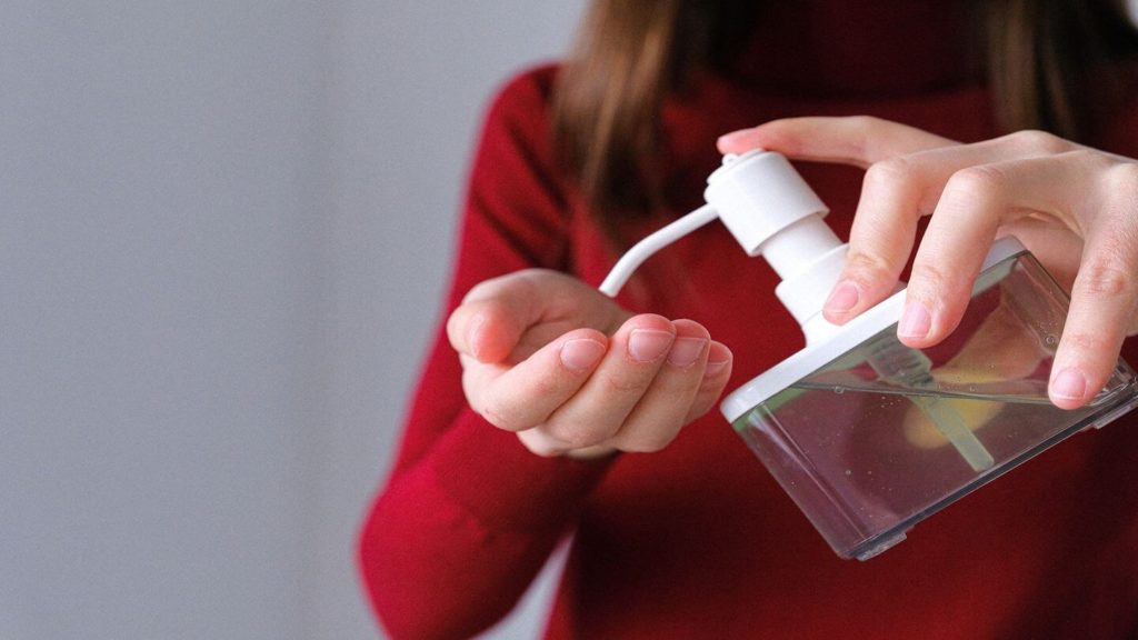 person using hand sanitiser travel hygiene kit