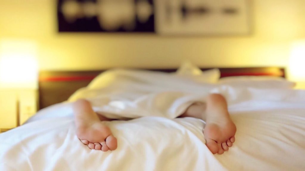 person sleeping in bed with feet sticking out