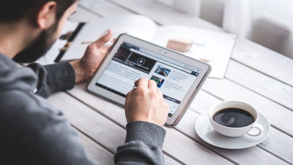 adult reading a tablet device with coffee