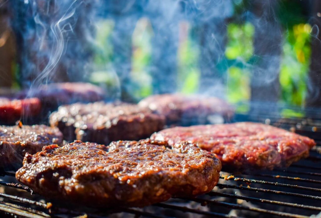 burgers cooking on a smoky grill South African braai