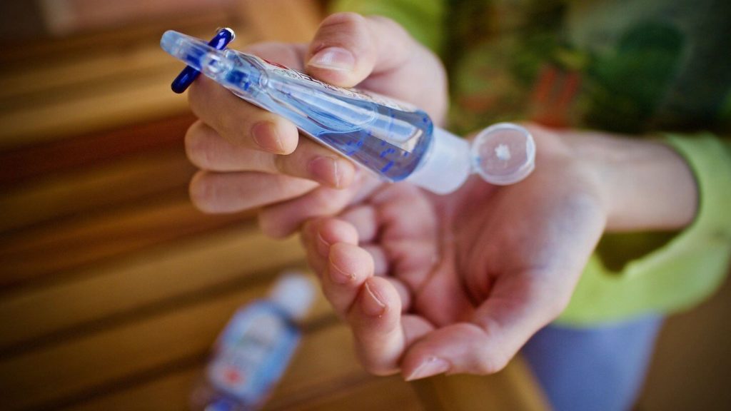 hands applying sanitiser from a bottle