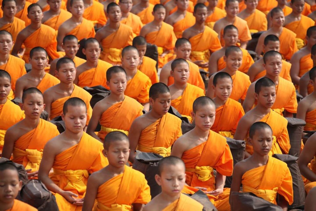 Des moines bouddhistes en robe orange méditant sur les traditions asiatiques