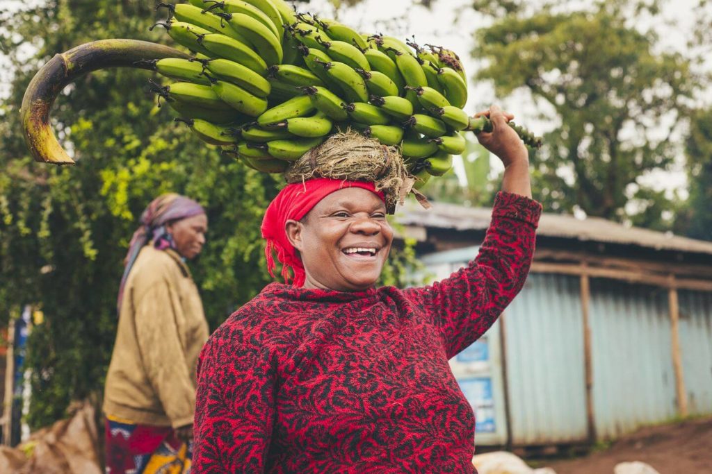 Kenyan woman carrying bunch of bananas on her head