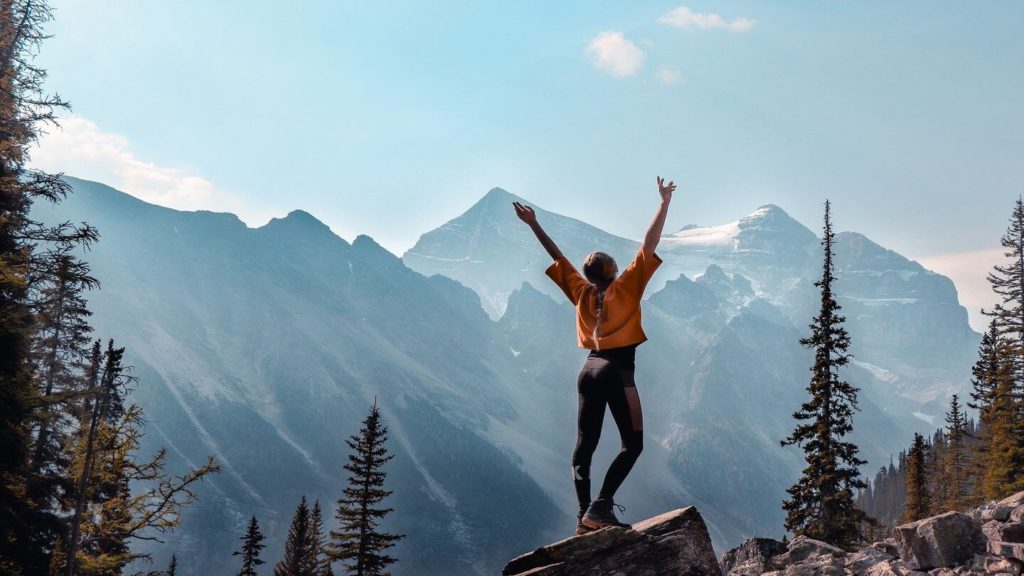 woman with arms outreached on a mountain peak
