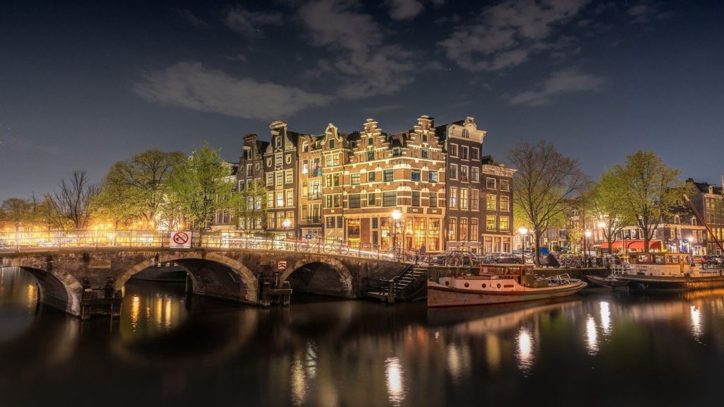 Amsterdam Old Town buildings bridge canal illuminated at night